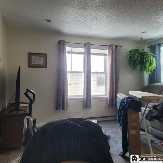 carpeted bedroom featuring a textured ceiling and a baseboard heating unit