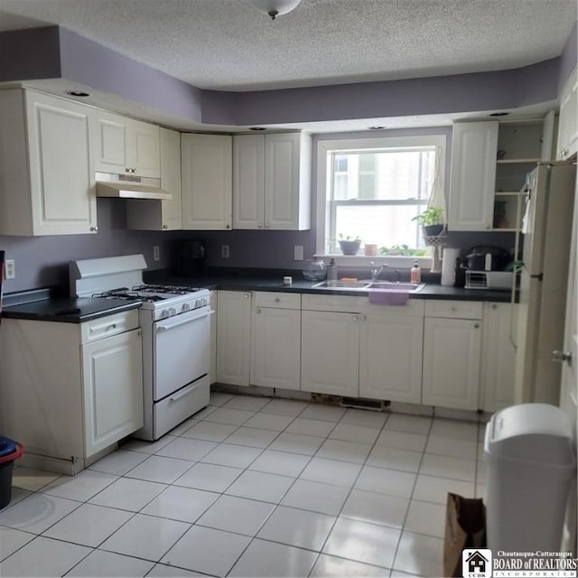 kitchen with white cabinets, white appliances, sink, and light tile patterned floors