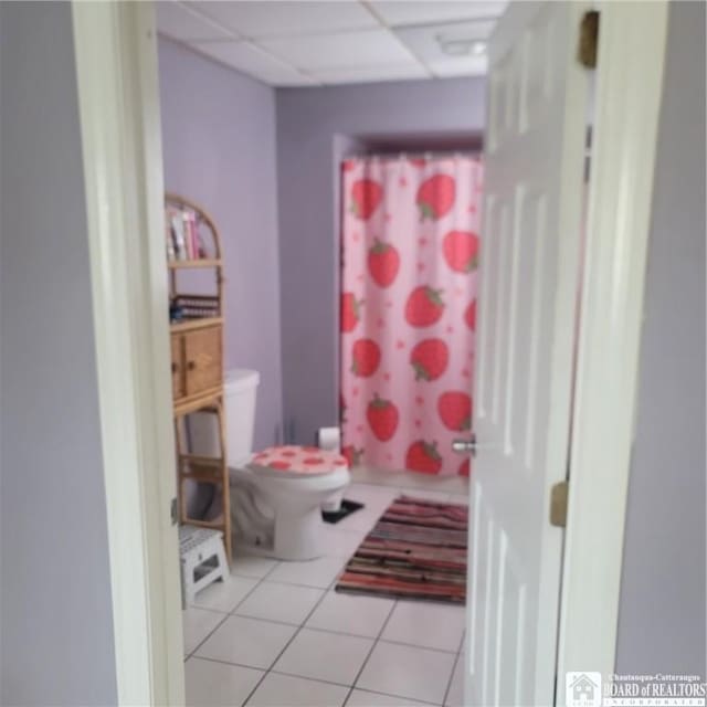 bathroom featuring tile patterned flooring, toilet, a drop ceiling, and walk in shower