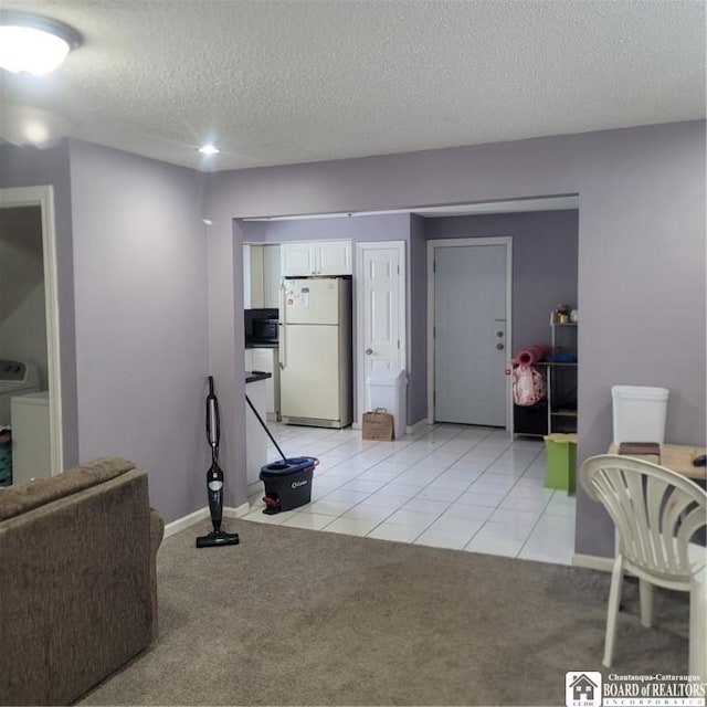 living room featuring a textured ceiling, washer / dryer, and light carpet