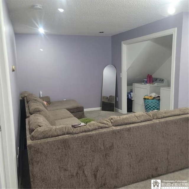 carpeted living room with a textured ceiling and washing machine and dryer