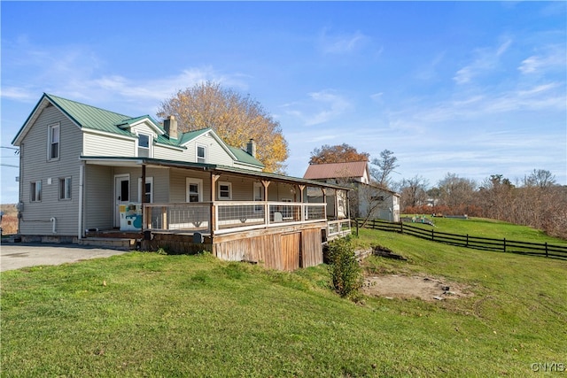 rear view of house featuring a lawn and covered porch