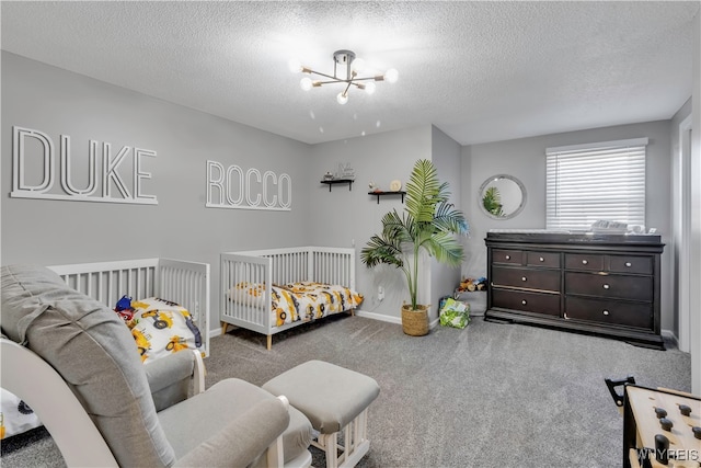 carpeted bedroom featuring a textured ceiling, a notable chandelier, and a crib