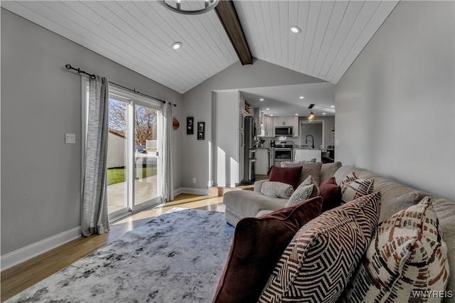 living room featuring wooden ceiling, sink, light wood-type flooring, and vaulted ceiling with beams