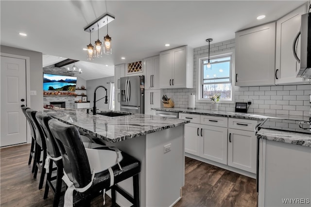 kitchen featuring dark wood-type flooring, sink, an island with sink, and stainless steel appliances