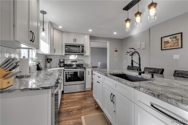 kitchen featuring stainless steel appliances, dark hardwood / wood-style flooring, white cabinets, sink, and pendant lighting