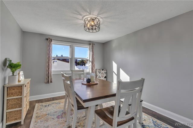 dining room featuring dark hardwood / wood-style flooring, a notable chandelier, and a textured ceiling