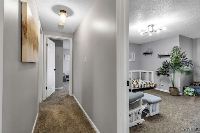 corridor featuring a chandelier, dark colored carpet, and a textured ceiling