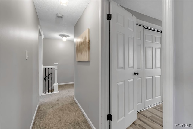 hall featuring a textured ceiling and light hardwood / wood-style floors