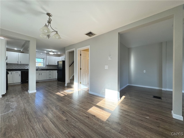 unfurnished living room with dark hardwood / wood-style flooring, a chandelier, and sink