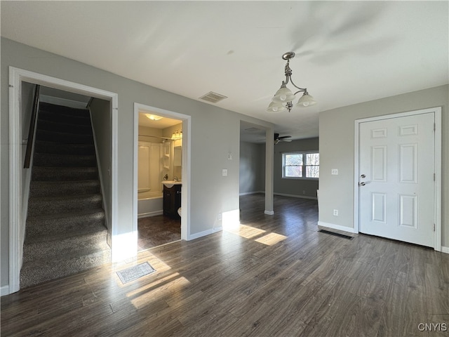 interior space featuring dark wood-type flooring and ceiling fan with notable chandelier