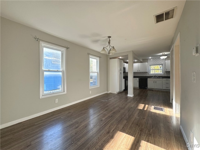 unfurnished living room featuring dark wood-type flooring, sink, and a notable chandelier