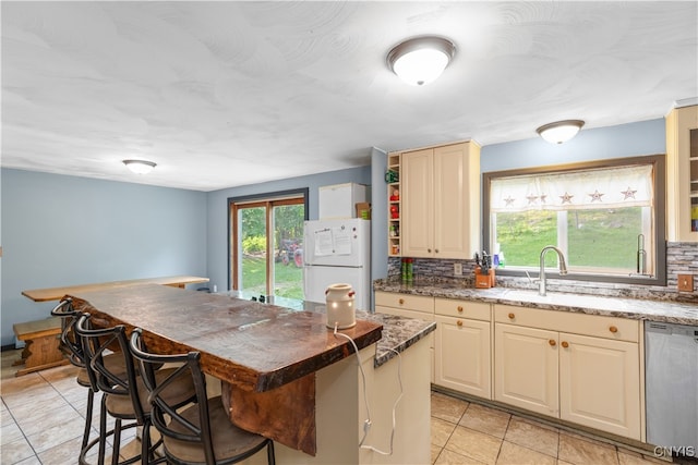 kitchen featuring a wealth of natural light, stainless steel dishwasher, a kitchen island, and white fridge