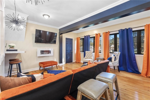 living room featuring a fireplace, hardwood / wood-style flooring, crown molding, and a notable chandelier