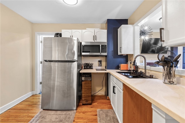 kitchen featuring appliances with stainless steel finishes, sink, light hardwood / wood-style floors, and white cabinets