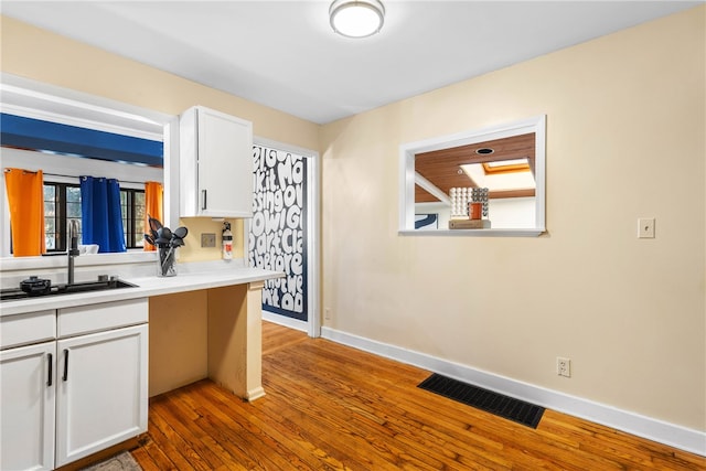 kitchen with white cabinetry, wood-type flooring, and sink