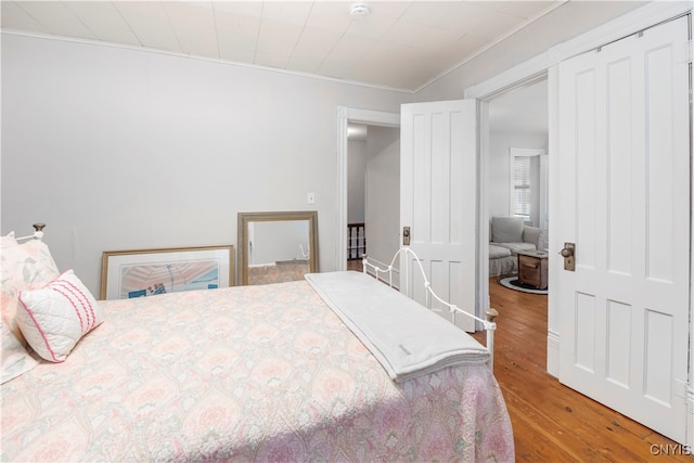 bedroom featuring wood-type flooring and crown molding