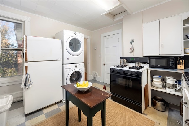 kitchen featuring white cabinets, plenty of natural light, black appliances, and stacked washer / dryer