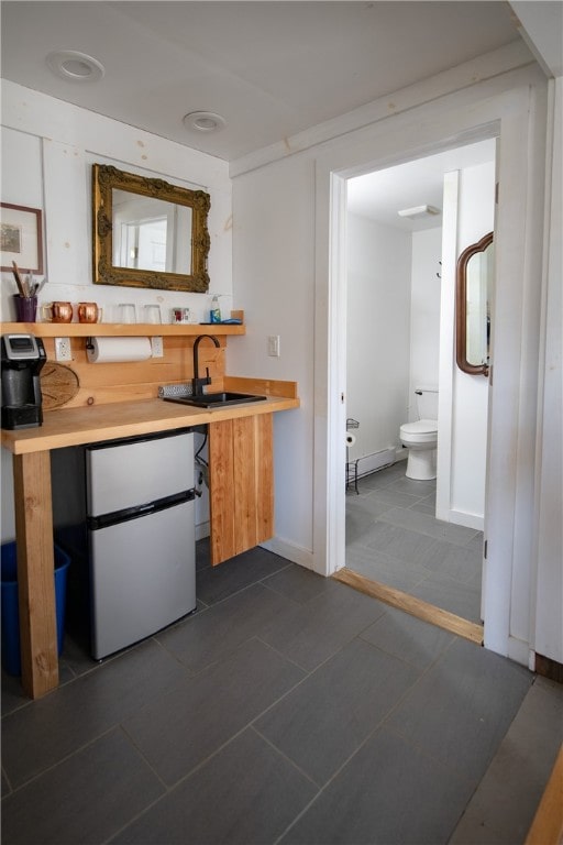 kitchen with dark tile patterned flooring, sink, and white fridge