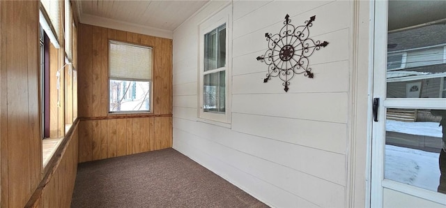 hall featuring carpet flooring, crown molding, and wooden walls