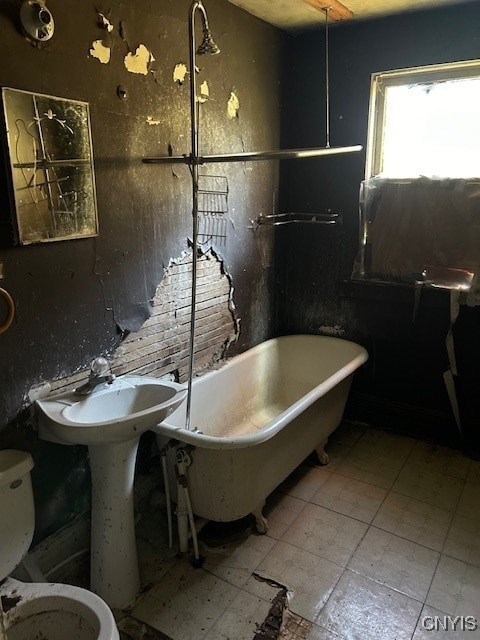 bathroom with a tub to relax in and toilet