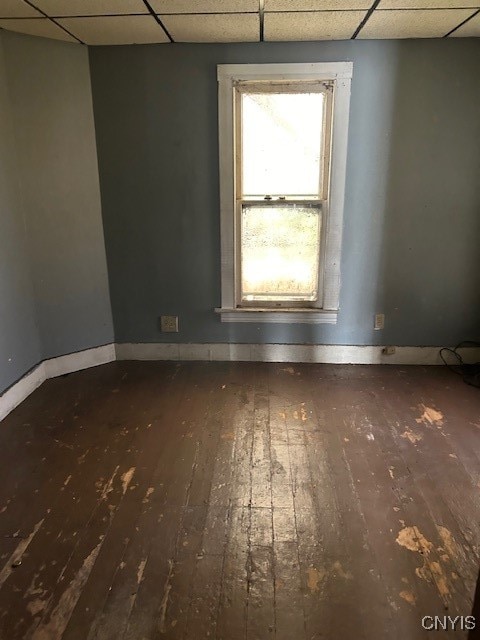 empty room featuring dark wood-type flooring and a paneled ceiling