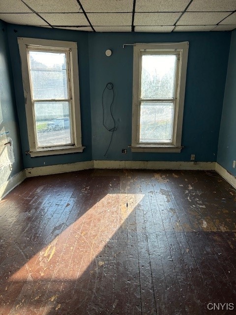 empty room with dark wood-type flooring, a paneled ceiling, and a wealth of natural light