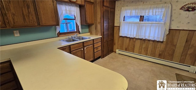 135 N 12th St, Olean, NY 14760 - kitchen with a baseboard heating unit, light countertops, wooden walls, brown cabinetry, and wallpapered walls