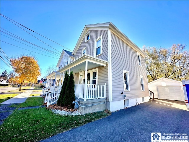 view of front of house featuring a garage, an outdoor structure, a front yard, and a porch