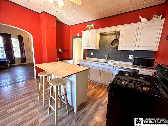 kitchen featuring hardwood / wood-style flooring, white cabinetry, sink, tasteful backsplash, and gas stove