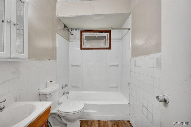 full bathroom featuring tiled shower / bath combo, toilet, vanity, tile walls, and hardwood / wood-style flooring