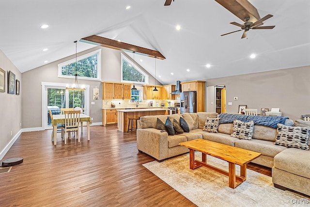 living room with high vaulted ceiling, light wood-type flooring, ceiling fan with notable chandelier, and beamed ceiling