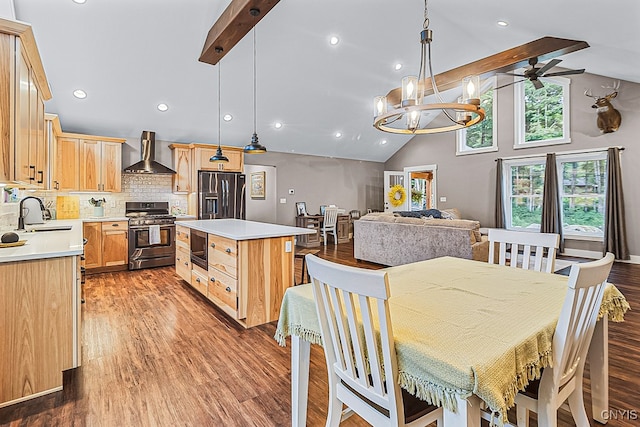 kitchen with stainless steel appliances, hardwood / wood-style flooring, sink, wall chimney exhaust hood, and a kitchen island