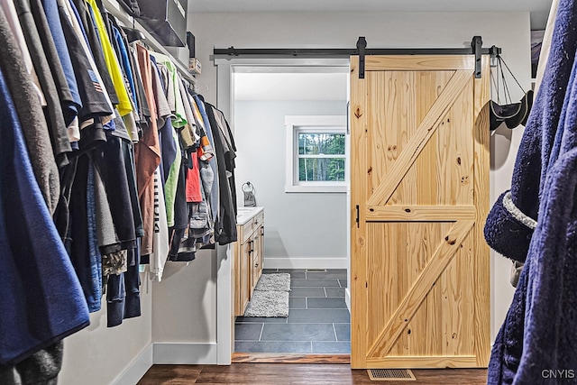 walk in closet featuring a barn door and dark hardwood / wood-style floors