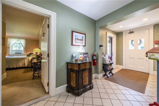 foyer entrance featuring cooling unit, light carpet, and crown molding