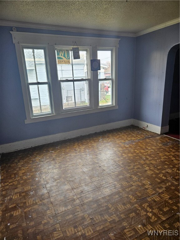 unfurnished room with a textured ceiling and ornamental molding