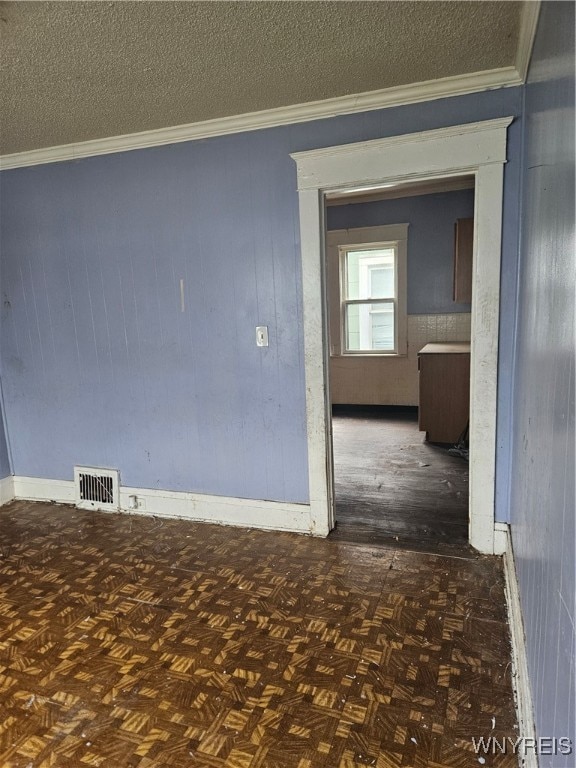 unfurnished room featuring dark parquet floors, a textured ceiling, and ornamental molding