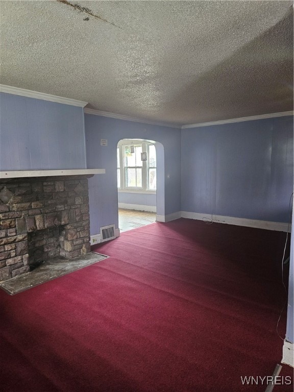 unfurnished living room with carpet flooring, a fireplace, a textured ceiling, and crown molding