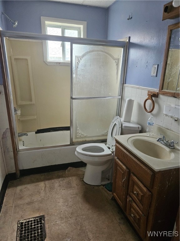 full bathroom with tile patterned flooring, vanity, combined bath / shower with glass door, and toilet