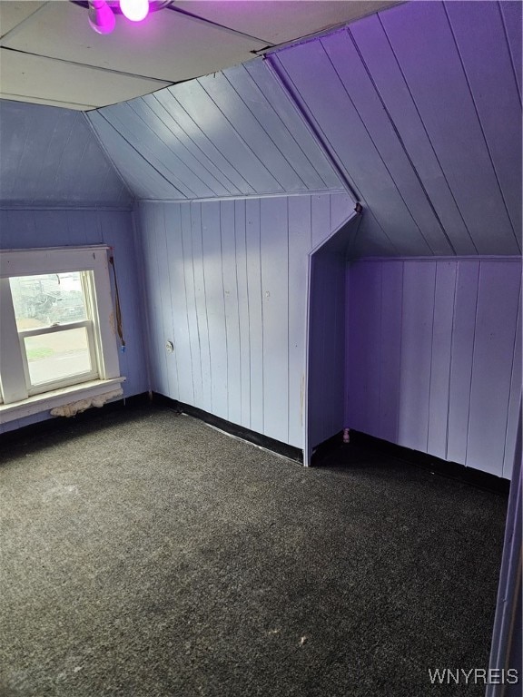 bonus room with carpet flooring, wood walls, and vaulted ceiling