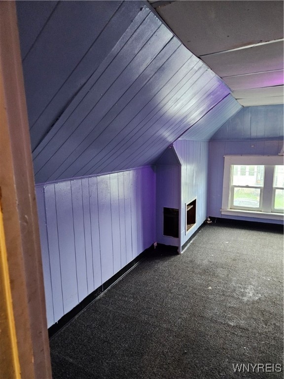 bonus room featuring wood walls, carpet floors, and vaulted ceiling