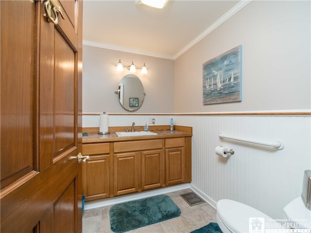 bathroom with wood walls, vanity, crown molding, tile patterned floors, and toilet