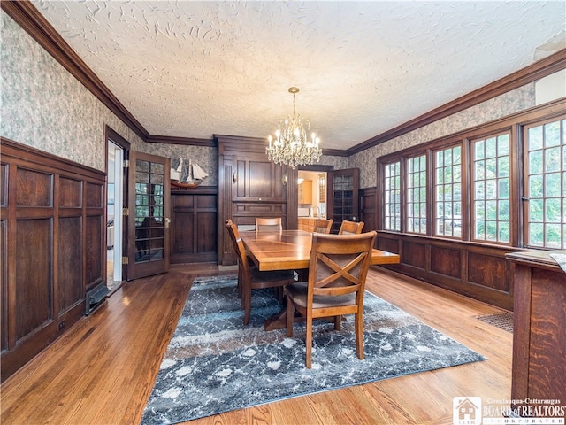 dining room featuring ornamental molding, wood-type flooring, a textured ceiling, and a chandelier