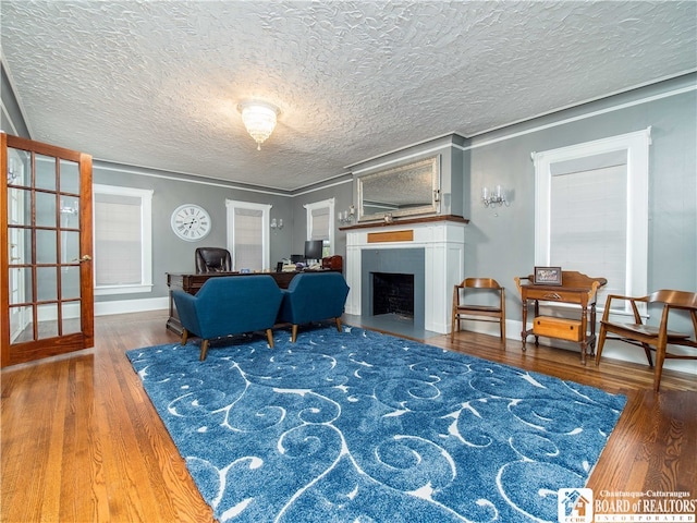 living room with dark wood-type flooring, a textured ceiling, and ornamental molding