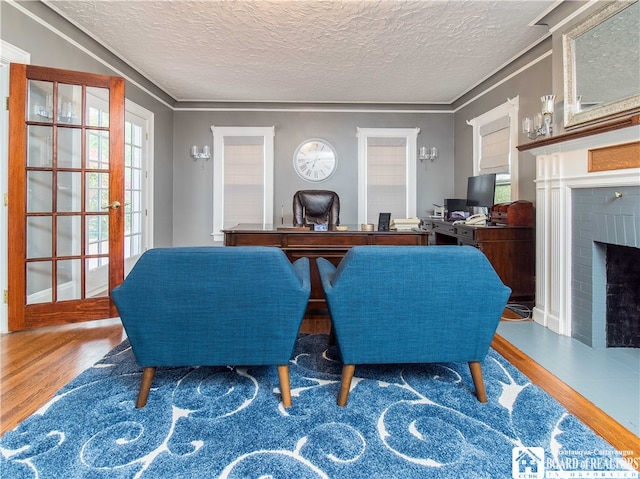 interior space with a brick fireplace, hardwood / wood-style flooring, a textured ceiling, and crown molding