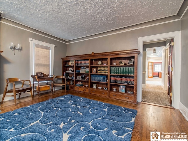 living area with hardwood / wood-style floors, ornamental molding, and a textured ceiling