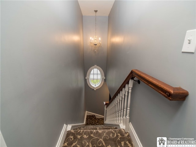 stairs with a notable chandelier