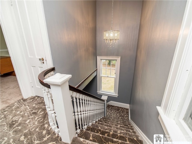 stairway featuring carpet flooring and an inviting chandelier