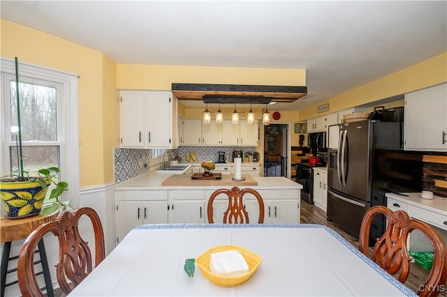 kitchen with pendant lighting, black appliances, sink, tasteful backsplash, and white cabinetry