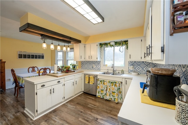 kitchen with kitchen peninsula, white cabinetry, stainless steel dishwasher, and sink